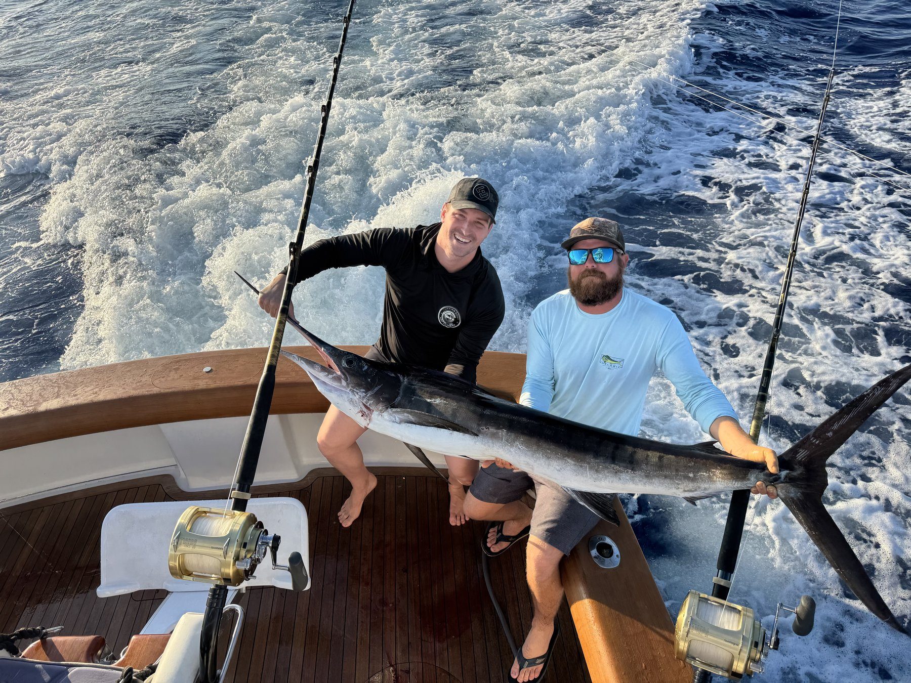 Two anglers holding a striped marlin